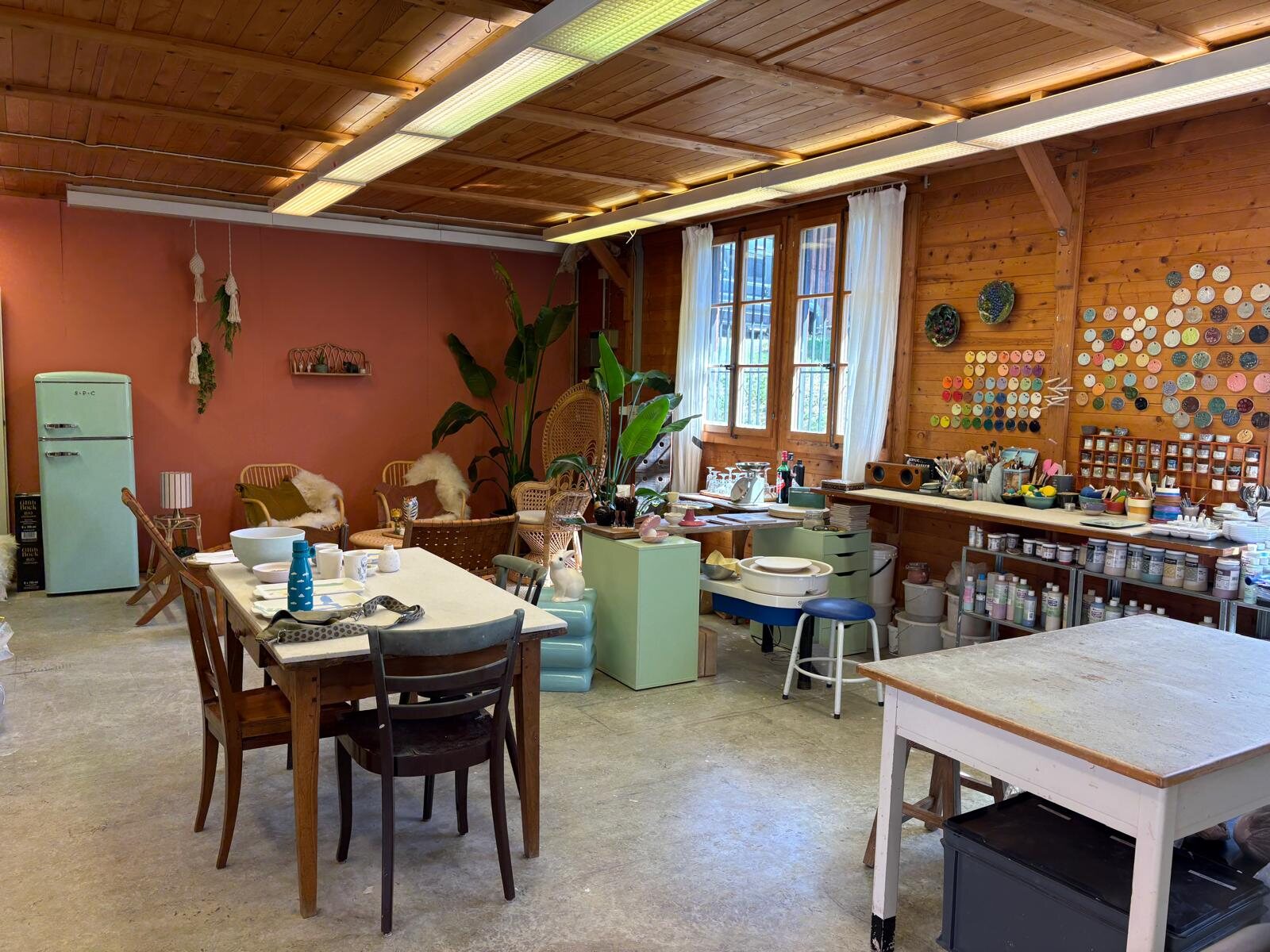 Das Atelier in der Alten Post: terrakottafarbene Wand, mintgrüner Kühlschrank, Holzdecke und Arbeitstische
