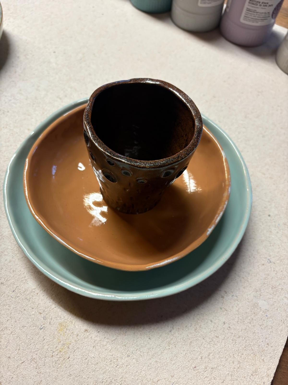 Brauner Becher in einer Terrakotta-Schale auf mintgrünem Teller