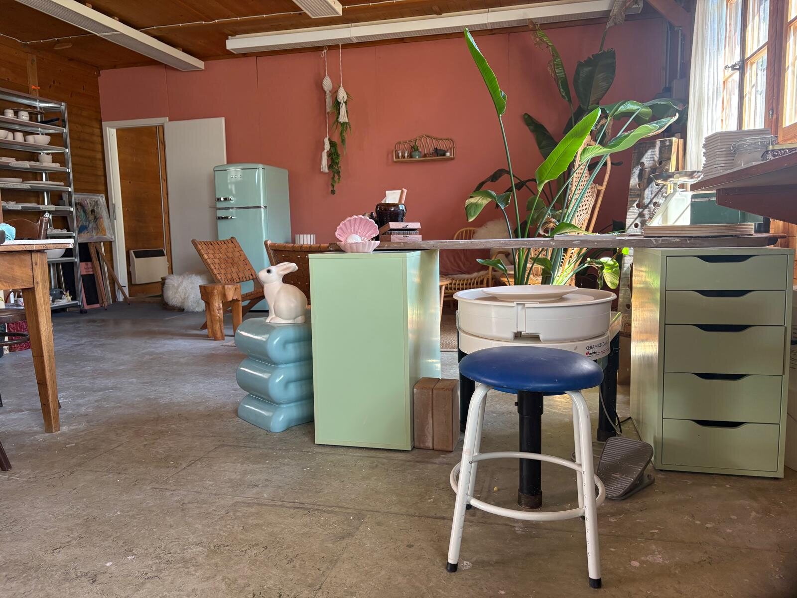 Blick ins Atelier mit Töpferscheibe und blauem Hocker